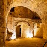 I gradoni ci conducono a 6 metri di profondit� in un ambiente scavato nella roccia calcerenitica, con al centro un sontuoso arco finemente decorato che ci lascia incantati
